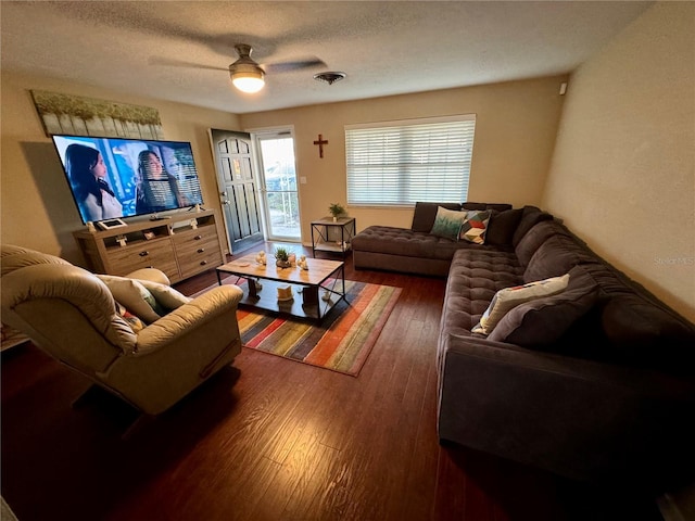 living room with ceiling fan, dark wood-type flooring, and a textured ceiling