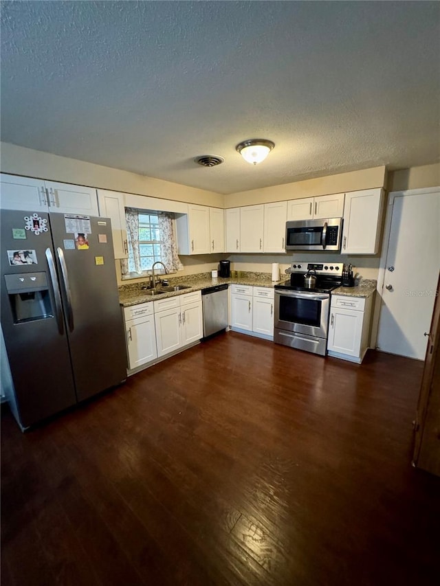 kitchen featuring light stone countertops, appliances with stainless steel finishes, dark hardwood / wood-style flooring, sink, and white cabinets