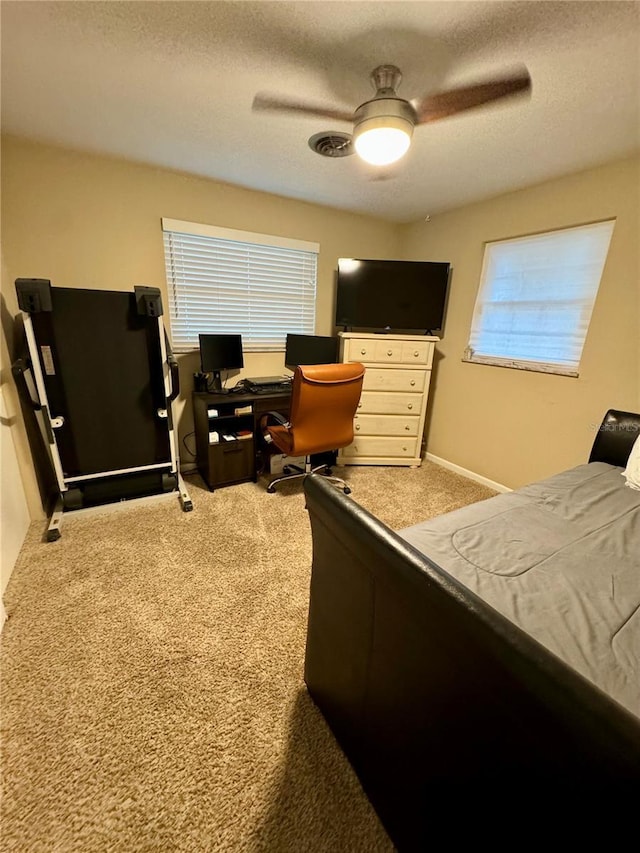 bedroom with multiple windows, ceiling fan, light carpet, and a textured ceiling