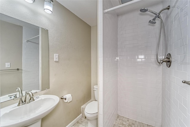 bathroom featuring tiled shower, sink, and toilet