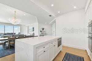 kitchen featuring white cabinets, pendant lighting, light wood-type flooring, and a kitchen island