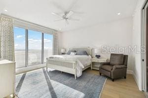 bedroom with ceiling fan, light hardwood / wood-style floors, a water view, and access to outside