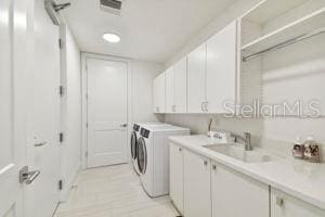 washroom with sink, cabinets, and independent washer and dryer