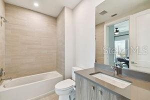 full bathroom with tiled shower / bath combo, toilet, and vanity