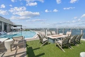 view of pool featuring a water view, a yard, and a patio