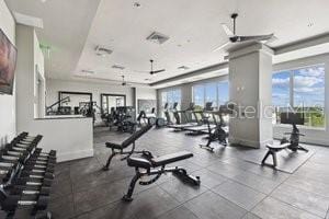 gym with a tray ceiling and ceiling fan