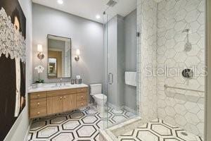 bathroom with an enclosed shower, vanity, toilet, and tile patterned flooring