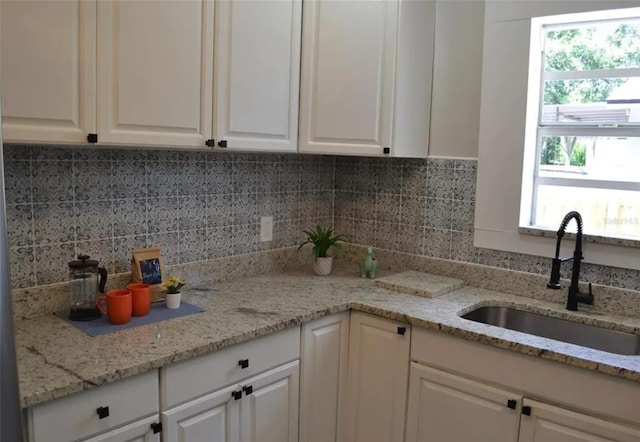 kitchen featuring white cabinetry, sink, light stone counters, and plenty of natural light