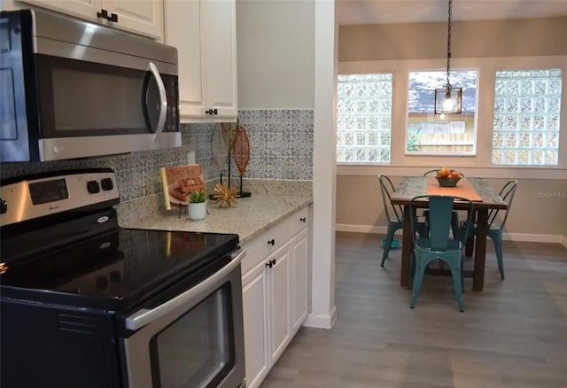 kitchen with pendant lighting, backsplash, light hardwood / wood-style floors, white cabinetry, and stainless steel appliances