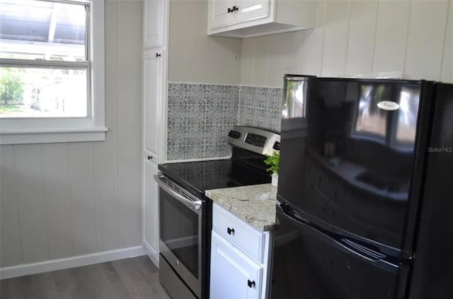 kitchen featuring dark hardwood / wood-style flooring, black fridge, light stone counters, white cabinetry, and stainless steel range with electric cooktop