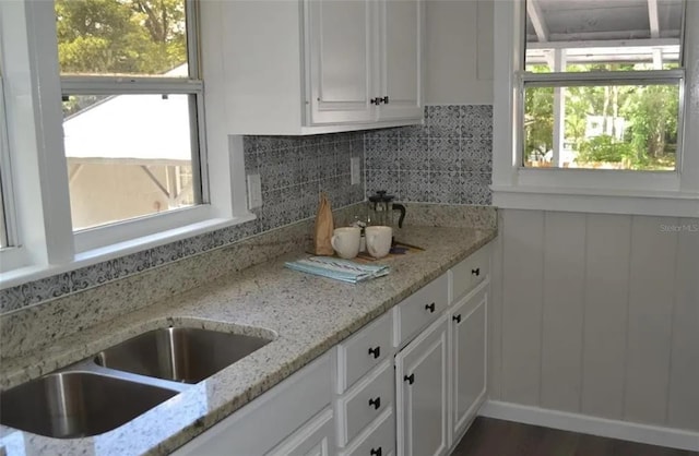 kitchen featuring backsplash, light stone counters, white cabinets, and dark wood-type flooring