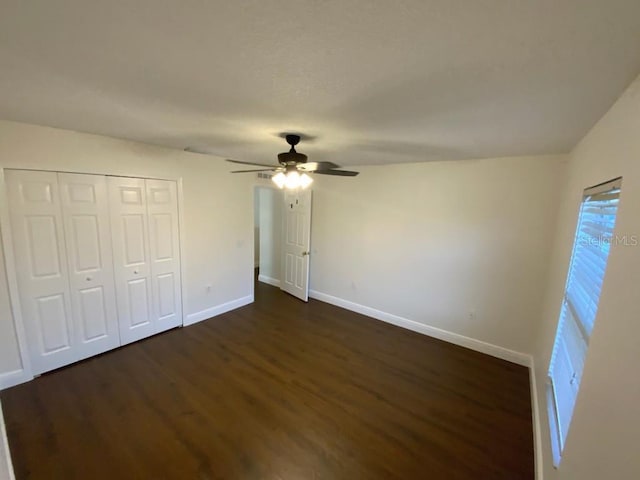 unfurnished bedroom featuring dark hardwood / wood-style flooring, a closet, and ceiling fan