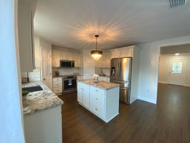 kitchen with decorative light fixtures, a kitchen island, white cabinetry, and stainless steel appliances