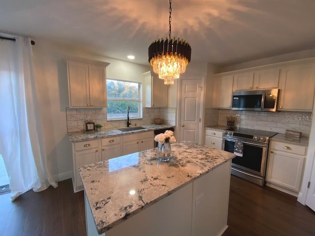 kitchen with sink, white cabinets, decorative light fixtures, and appliances with stainless steel finishes