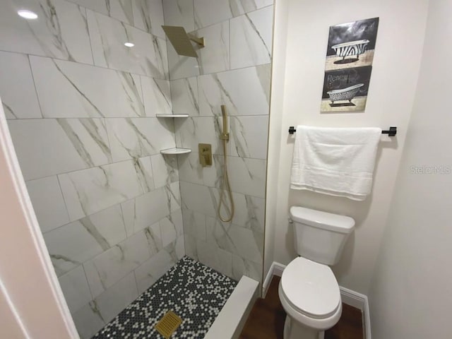 bathroom featuring toilet and a tile shower