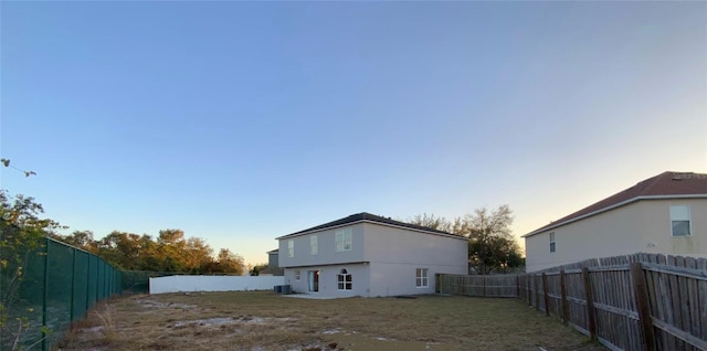 back house at dusk featuring central AC