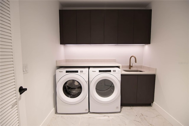 clothes washing area featuring cabinets, washing machine and dryer, and sink