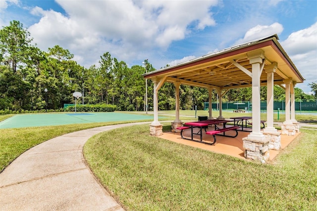 view of home's community with basketball court and a lawn