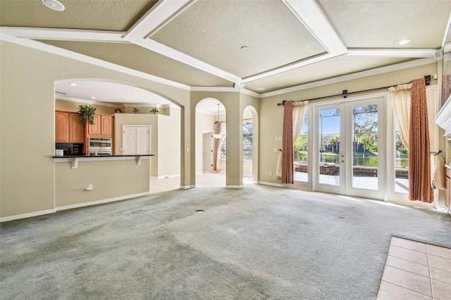 unfurnished living room with crown molding, light colored carpet, french doors, and a textured ceiling