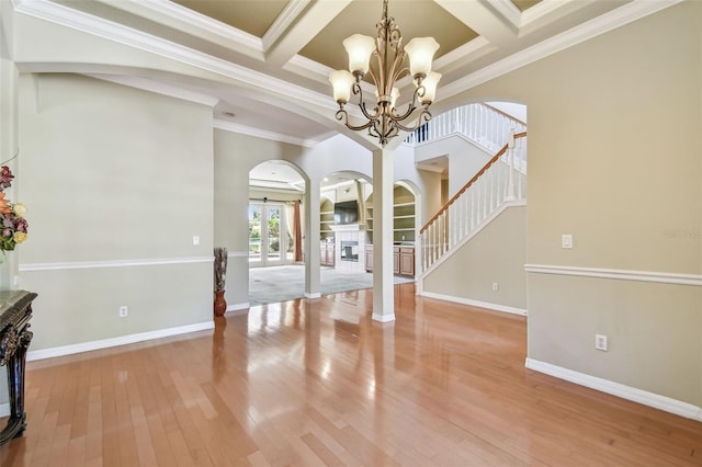 foyer entrance featuring coffered ceiling, wood-type flooring, a chandelier, ornamental molding, and beam ceiling