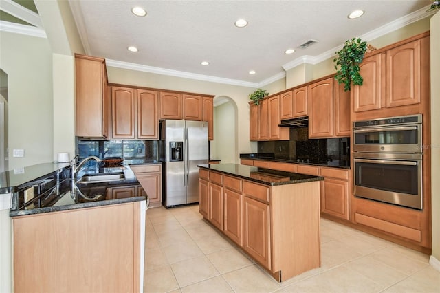 kitchen with light tile patterned floors, sink, stainless steel appliances, tasteful backsplash, and dark stone counters