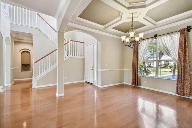 empty room with crown molding, a chandelier, coffered ceiling, wood-type flooring, and beamed ceiling