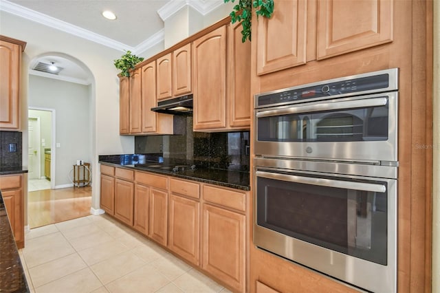 kitchen featuring ornamental molding, dark stone countertops, stainless steel double oven, and decorative backsplash