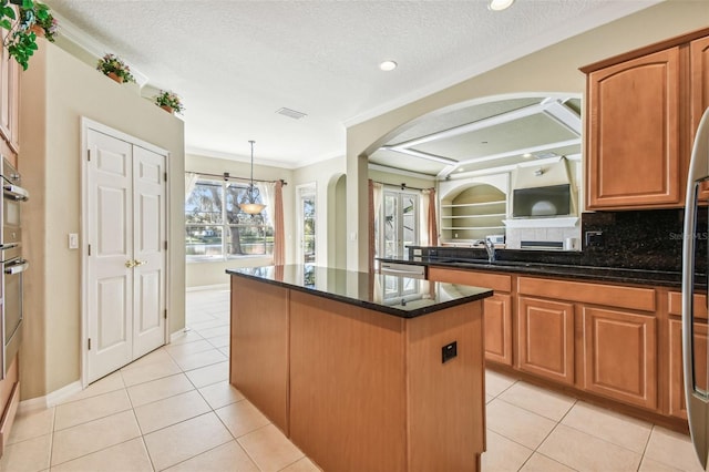 kitchen featuring light tile patterned floors, crown molding, dark stone countertops, a textured ceiling, and a kitchen island