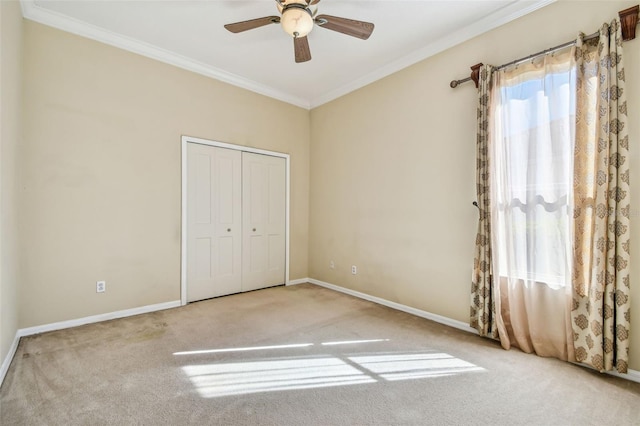 unfurnished bedroom featuring crown molding, ceiling fan, carpet flooring, and a closet