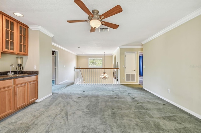 unfurnished living room featuring light carpet, sink, ornamental molding, and ceiling fan