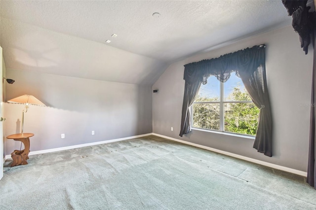 additional living space featuring carpet flooring, vaulted ceiling, and a textured ceiling