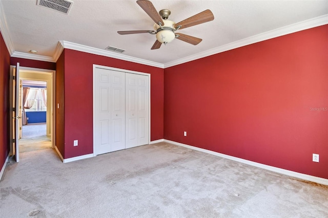 unfurnished bedroom with crown molding, light carpet, ceiling fan, and a closet