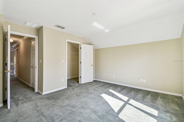 unfurnished bedroom with a spacious closet, vaulted ceiling, ornamental molding, carpet flooring, and a closet