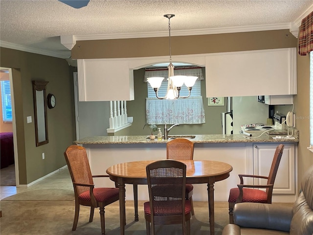 dining area with a textured ceiling, ornamental molding, sink, and a chandelier