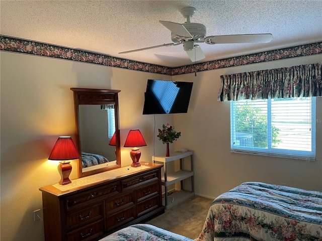 bedroom with ceiling fan, carpet floors, and a textured ceiling