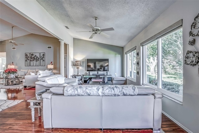 living room featuring a textured ceiling, ornate columns, dark wood-type flooring, and lofted ceiling