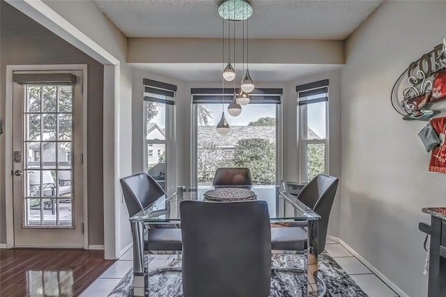 dining area with a wealth of natural light, wood-type flooring, and a textured ceiling