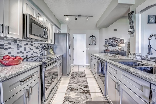 kitchen featuring light stone countertops, stainless steel appliances, tasteful backsplash, and sink