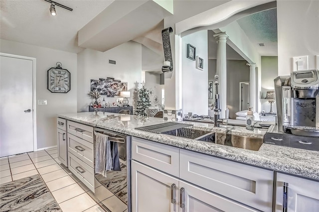 kitchen with ornate columns, white cabinetry, light stone counters, a textured ceiling, and light tile patterned floors