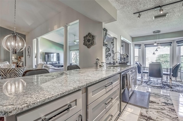 kitchen featuring a center island with sink, ornate columns, a textured ceiling, and a wealth of natural light