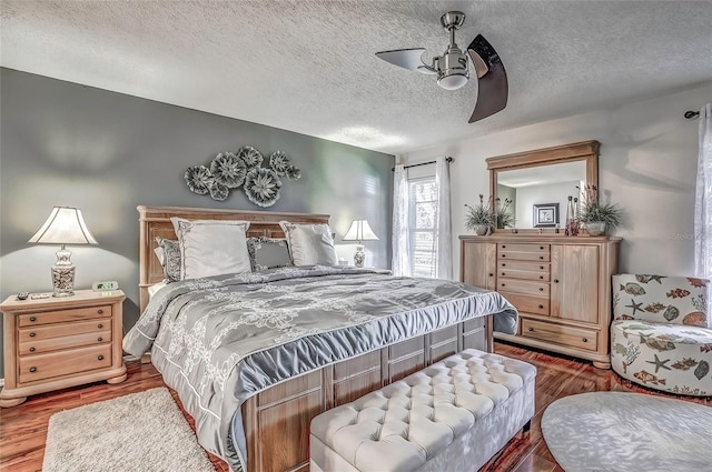 bedroom with ceiling fan, a textured ceiling, and hardwood / wood-style flooring