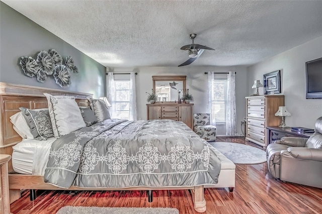 bedroom with hardwood / wood-style floors, ceiling fan, and a textured ceiling