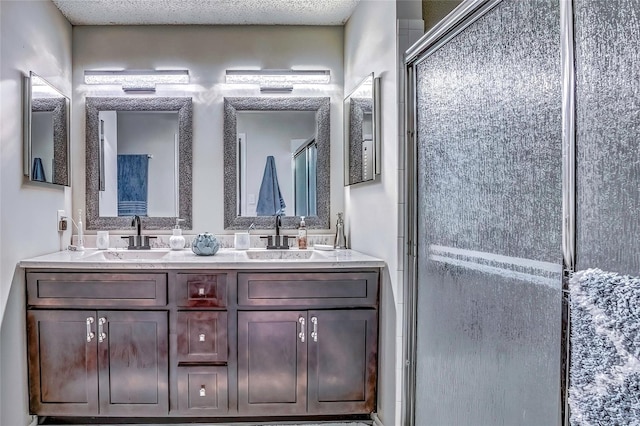 bathroom with a shower with door, vanity, and a textured ceiling