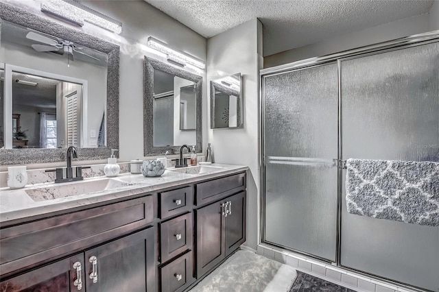 bathroom featuring ceiling fan, a shower with door, vanity, and a textured ceiling