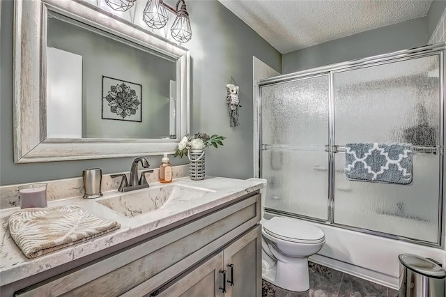 full bathroom featuring vanity, a textured ceiling, toilet, and bath / shower combo with glass door