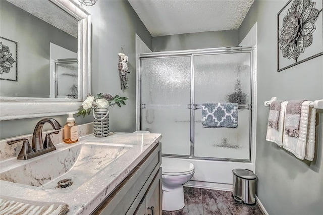 full bathroom featuring toilet, vanity, a textured ceiling, and combined bath / shower with glass door