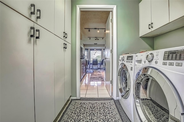 laundry room featuring light tile patterned flooring, cabinets, separate washer and dryer, and a textured ceiling