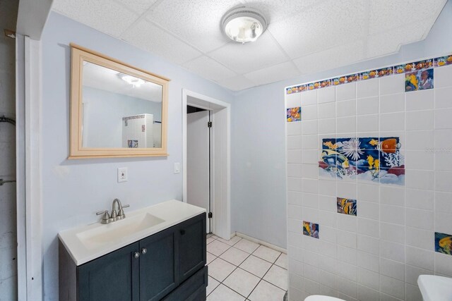 bathroom featuring toilet, vanity, tile patterned floors, and a drop ceiling