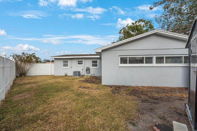 rear view of property with a lawn and central air condition unit