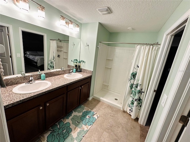 bathroom with tile patterned floors, curtained shower, vanity, and a textured ceiling